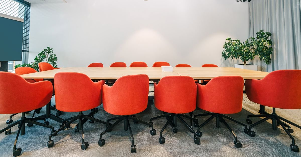 Empty boardroom with red chairs and a long conference table