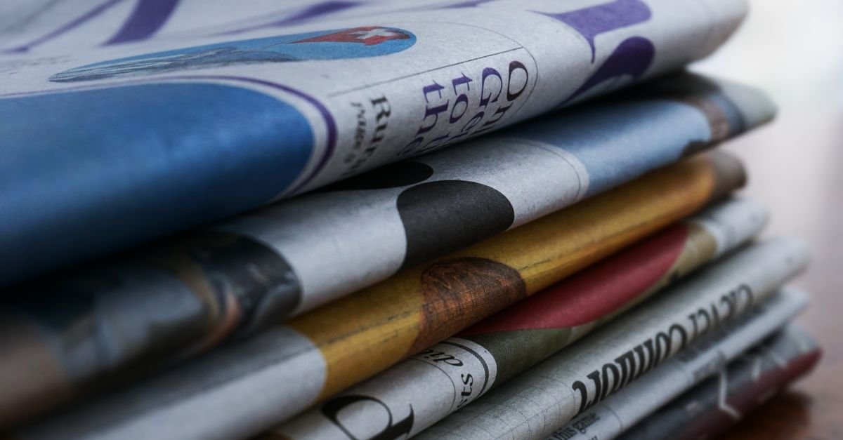 Close-up of newspapers stacked on a table, illustrating general media coverage